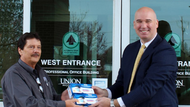 Jared Goulding presents masks to Union Hospital's Doug Smith.