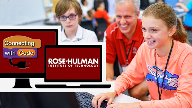 Image shows a smiling David Fisher observing a young person working at a computer. 