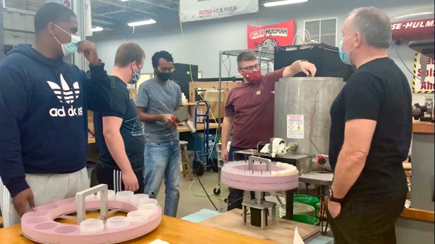 Image shows four students talking with company owner inside a Rose-Hulman innovation space.