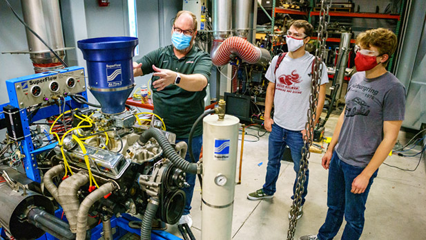 Image shows students working in a lab with a professor giving them instructions.