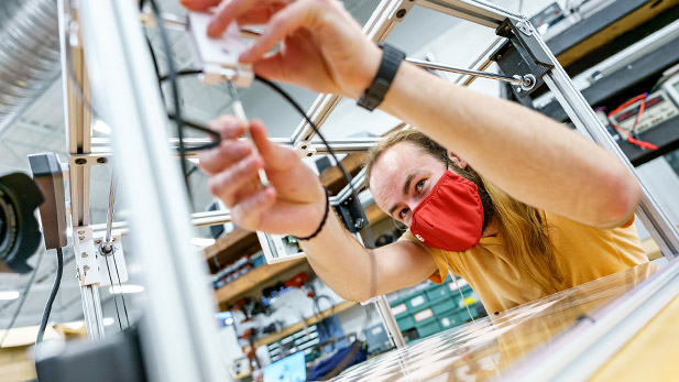 Image shows a student wearing a protective mask working on a Rose Show project.