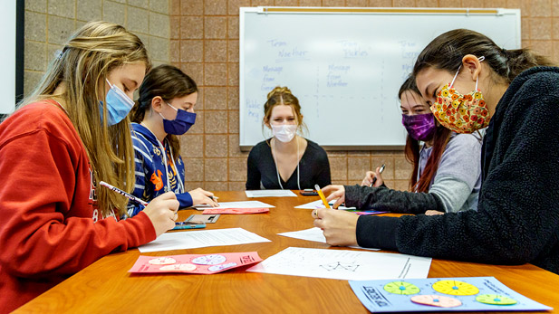 A group of students sit at a table working on math problems.