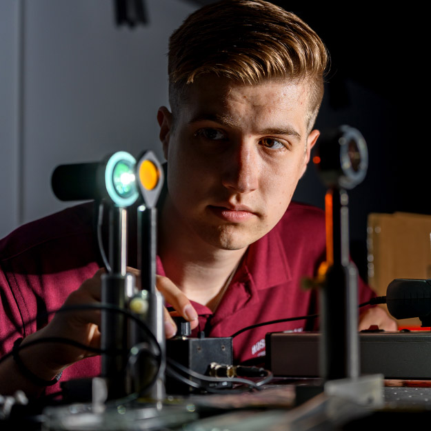 Ryan Brown, Andrew Nichols, Elijah Johnson, and Evan O’Brien (pictured L-R) pose  in front of optical devices.