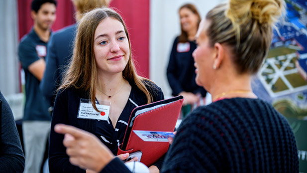 A female student speaks with a recruiter during the Fall Career Fair 2025, engaging in networking and exploring job opportunities.