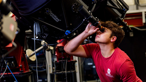 Male student looking into an Oakley Observatory telescope.