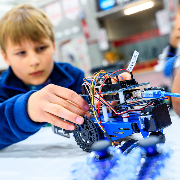 Two students work together to wire a robot.