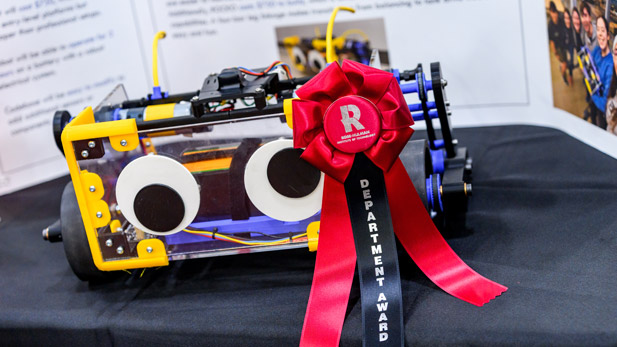 A robot with googly eyes and a department award ribbon.
