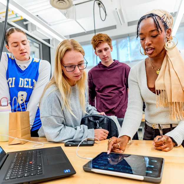Biomedical engineering students demonstrate their device, which clips onto the brim of a baseball cap.