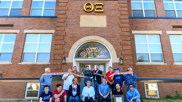 Theta Xi alumni and students and Erik Hayes cut a ribbon in fron of the new house.