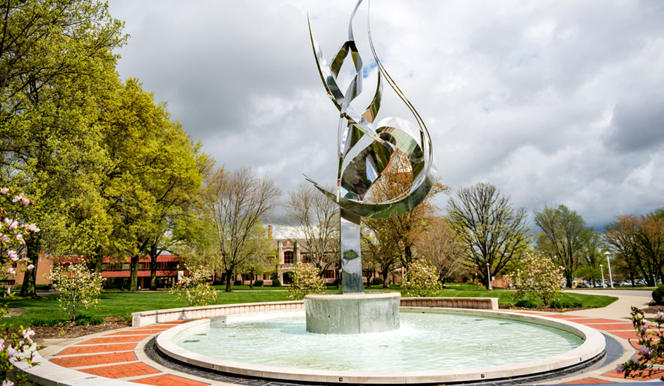 The Flame of the Millennium sculpture and fountain on a cloudy day. 